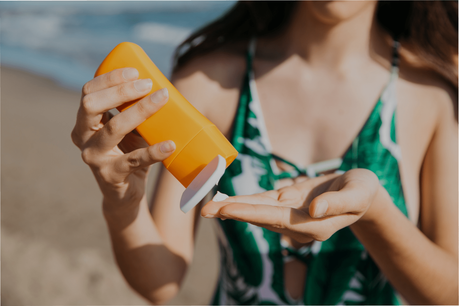 uma mulher branca passando protetor para se proteger do Câncer de Pele